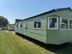 a green trailer parked in a grass field at Cabana Escape in Little Clacton