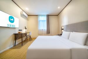 Una habitación de hotel con una cama grande y un escritorio. en Hanting Shanghai Jufeng Road Subway Station Branch, en Shanghái