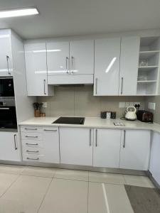 a white kitchen with white cabinets and a sink at Itowers Luxury Apartment in Gaborone +6 photos