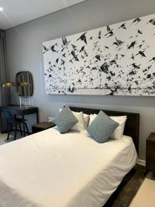 a bedroom with a white bed with birds on the wall at Itowers Luxury Apartment in Gaborone