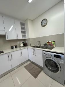 a kitchen with a washing machine and a clock on the wall at Itowers Luxury Apartment in Gaborone