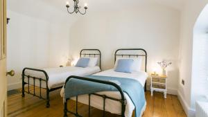 Habitación con 2 camas, paredes blancas y suelo de madera. en Ty Capel Mawr, en Menai Bridge