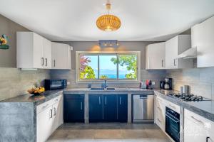 a kitchen with blue cabinets and a window at Villa Eden... pour un séjour parfait! in Saint-Leu