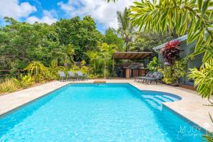 a pool in a backyard with chairs and trees at Villa Eden... pour un séjour parfait! in Saint-Leu