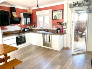 a kitchen with white cabinets and red walls at La Maison Nikaïa in Narbonne