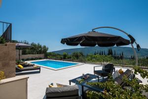 a patio with an umbrella and a swimming pool at Villa Casa de Flores in Dubravka