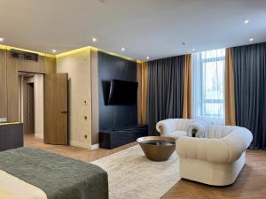 een kamer met een bed en twee stoelen en een televisie bij Donatello Boutique Hotel in Alma-Ata +40 foto's
