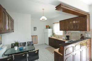 eine Küche mit Holzschränken und einem Tisch mit Stühlen in der Unterkunft Evaggelatos Cottage in Lixouri + 43 Fotos