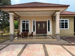 a small house with a wooden door and a patio at RNK BoutiQue HOTEL in Jitra