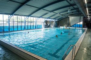 a large swimming pool with people in the water at Strandnahes Ferienhaus mit Garten hundefreundlich MeerZeit Ameland in Buren
