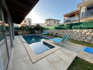 a swimming pool with a blue chair next to a building at Derya Beach Agullu Villa 6 in Kaş