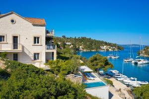 a house on a hill next to a marina with boats at VILLA PHILIPPA - luxurious five-room villa - idyllic location - first row to the sea - spectacular view of the sea bay - unforgettable sunsets - 15 minutes from Supetar ferry port - free parking - private heated pool in Sutivan