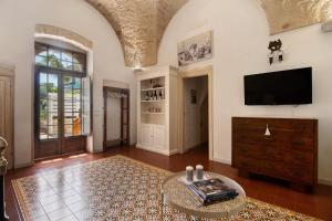 Una sala de estar con un televisor de pantalla plana y una mesa. en La Dimora dello Zio, with pool, en Ostuni