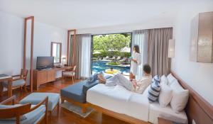 a man and woman sitting on a bed in a hotel room at Woodlands Suites Serviced Residences - SHA Extra Plus in Pattaya North