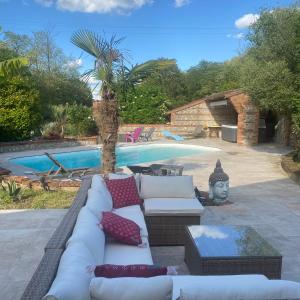 a patio with a couch and a swimming pool at Toulousaine de 200 m2 10 pers Piscine Jacuzzi proche de Toulouse in Lagrâce-Dieu