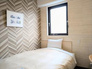 a small bedroom with a bed and a window at Morioka New City Hotel in Morioka