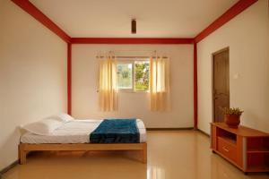 ein Schlafzimmer mit einem Bett und einem Fenster in der Unterkunft Grill & Chill by Bored Ape Hostels - Kotagiri in Kotagiri