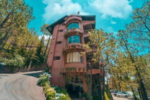 卡绍利Pine Vista Resort !! A Complete Resort with all Facilities # A Beautiful Mountain View # Best Selling Property的前面有树木的红砖建筑