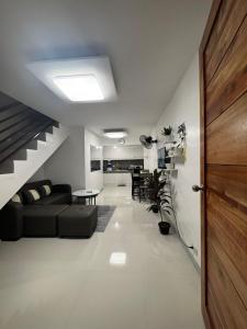 a living room with a black couch and a staircase at D&D Transient House in Sampong