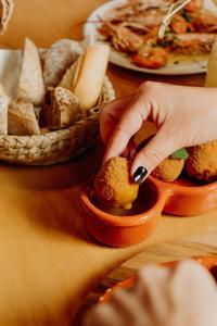 a person putting food into a bowl on a table with bread at Velamar Boutique Hotel - Adults Friendly in Albufeira