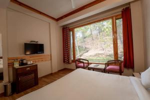 卡绍利Pine Vista Resort !! A Complete Resort with all Facilities # A Beautiful Mountain View # Best Selling Property的酒店客房,设有床铺和带椅子的窗户。