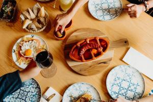 a table with plates of food and people holding a glass of wine at Velamar Boutique Hotel - Adults Friendly in Albufeira