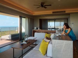 a woman standing in a living room with a couch and a table at seven x seven ISHIGAKI in Ishigaki Island