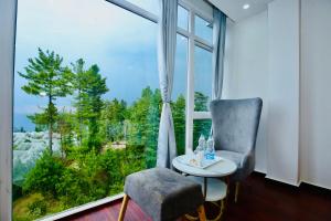 a room with a chair and a table and a large window at Hotel White Crest Kufri - Mountain View Rooms in Kūfrī