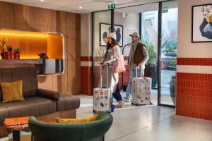 zwei Personen stehen mit Gepäck in einer Ladenlobby in der Unterkunft Yuna Montmartre - ApartHotel in Paris