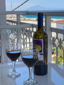 two glasses of red wine next to a bottle of wine at Luxury Rooms Naoum - Adults only in Limenaria