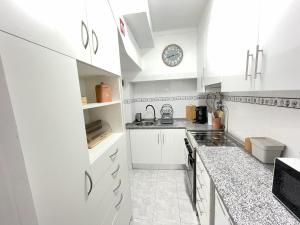 a kitchen with white cabinets and a clock on the wall at Sesimbra Fé House in Sesimbra