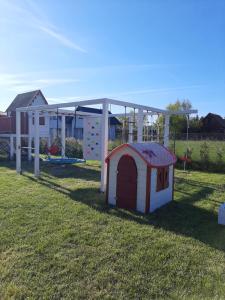 a dog house and a play structure in a yard at Osada Szwedzka Domek Plus in Rusinowo