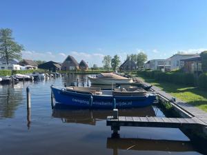 un gruppo di imbarcazioni è ormeggiato presso un molo di Camping Kleine Belterwijde, Pod, Tiny House aan het water a Belt-Schutsloot