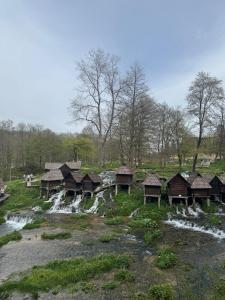 a group of huts in a field with a waterfall at Lake House Ceric in Jajce