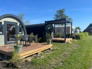 una casa con terrazza con sedie e gazebo di Camping Kleine Belterwijde, Pod, Tiny House aan het water a Belt-Schutsloot Altre 11 foto