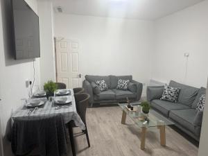 a living room with two couches and a table at Britlodge Ruskin Ave Home in Manchester