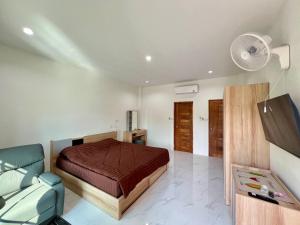 a bedroom with a bed and a couch and a fan at บุณยาเพลส เด่นชัย แพร่ in Den Chai