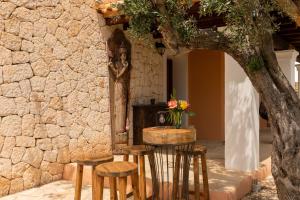 a table with stools in front of a stone wall at Villa Beni - Santa Eulalia in Santa Eularia des Riu