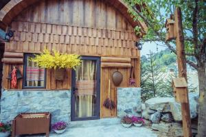 a wooden house with flowers in front of it at Bắc Hà Green Homestay & Coffe in Kon Rung (1)
