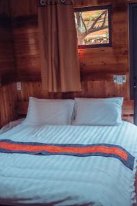 a bed with white pillows and a window in a room at Bắc Hà Green Homestay & Coffe in Kon Rung (1)