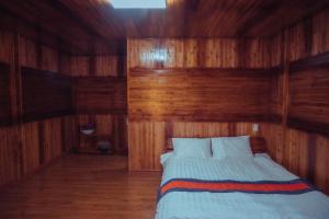 a bedroom with a bed with wooden walls and wooden floors at Bắc Hà Green Homestay & Coffe in Kon Rung (1)