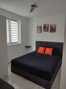 a bedroom with a black bed with two orange pillows at Apartman Nina in Ostrovo +22 photos