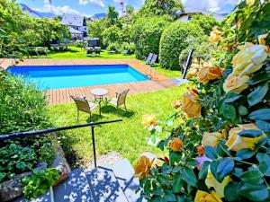 una piscina in un cortile con sedie e fiori di Garni Tschutscherhof a Laion