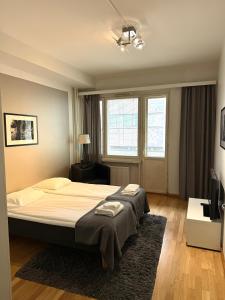 une chambre avec un grand lit et une télévision dans l'établissement Kotimaailma Apartments Kamppi - 2BR in the city center with code lock, à Helsinki