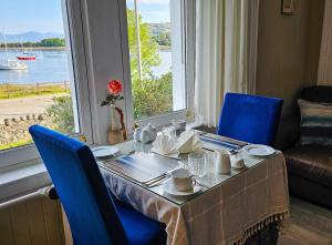 ein Esstisch mit blauen Stühlen und ein großes Fenster in der Unterkunft Ards House in Oban