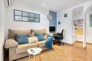 ein Wohnzimmer mit einer Couch und einem Schreibtisch mit einem Computer in der Unterkunft La Terraza De Palmeres in Mareny Barraquetas