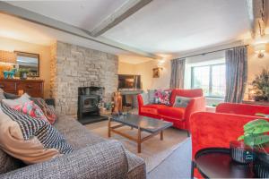a living room with red furniture and a stone fireplace at Bay Tree Cottage in Burton Bradstock