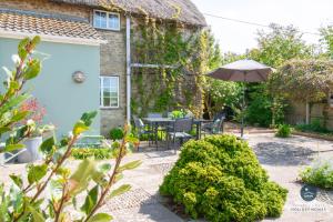 a garden with a table and an umbrella at Bay Tree Cottage in Burton Bradstock