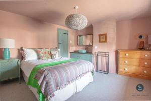 a bedroom with a bed with a green and white blanket at Bay Tree Cottage in Burton Bradstock
