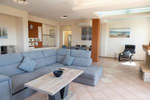 a living room with a blue couch and a table at Aethra Villa in Sounio